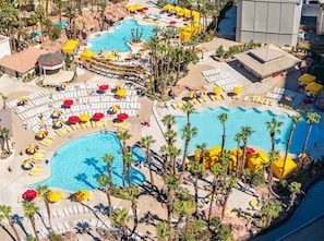 A resort with multiple swimming pools, sun loungers, and palm trees.