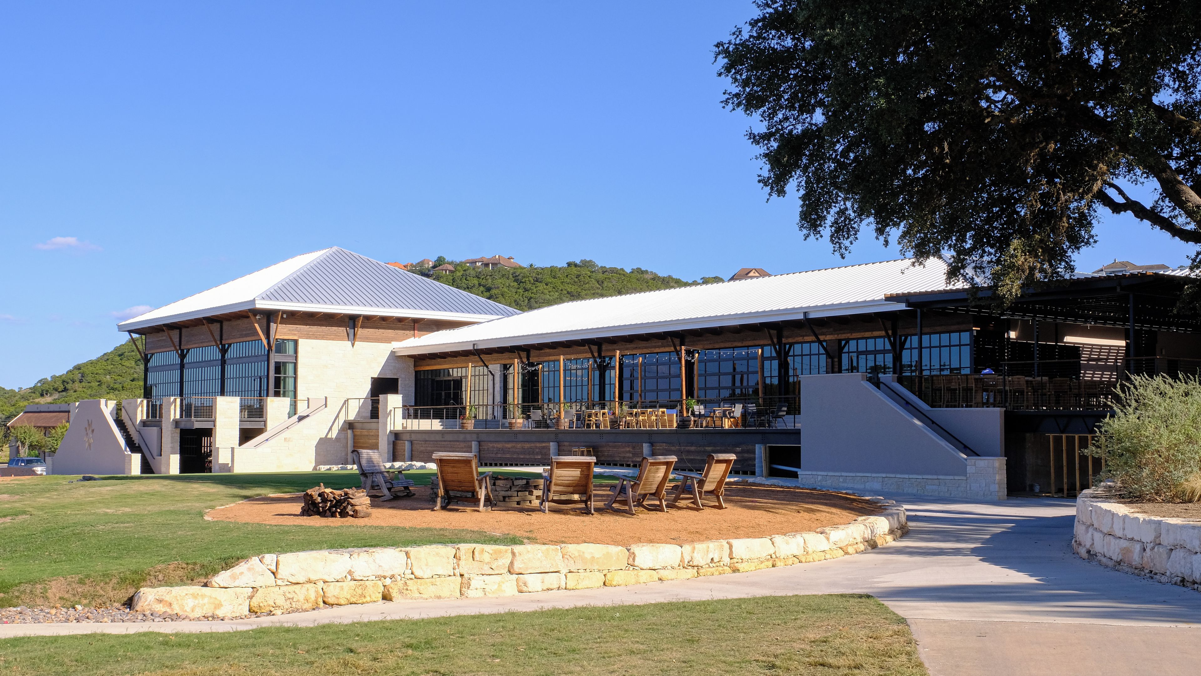 A modern building with a covered outdoor seating area and a staircase leading to an upper level.