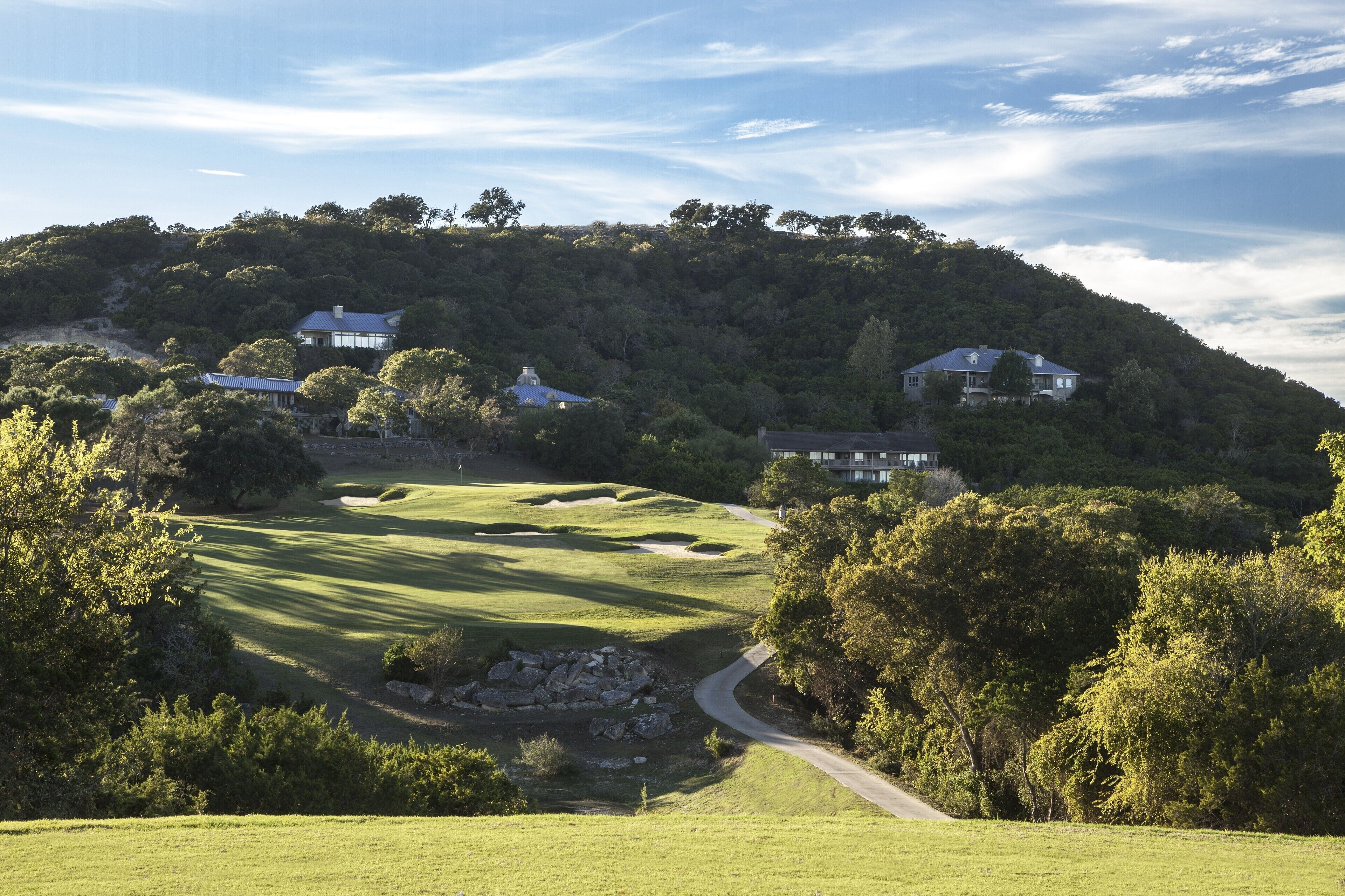 A golf course with multiple houses on a hillside.