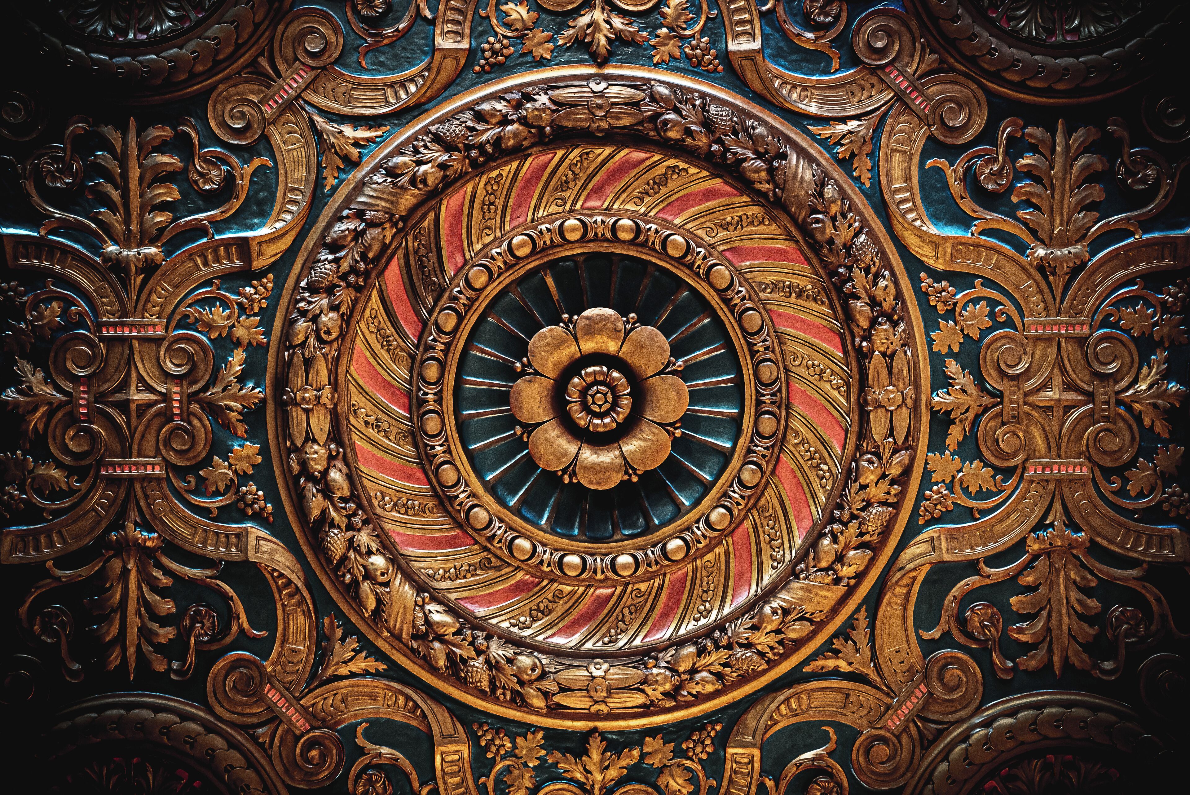 A detailed, ornate ceiling with a central circular design surrounded by intricate patterns and gold accents.