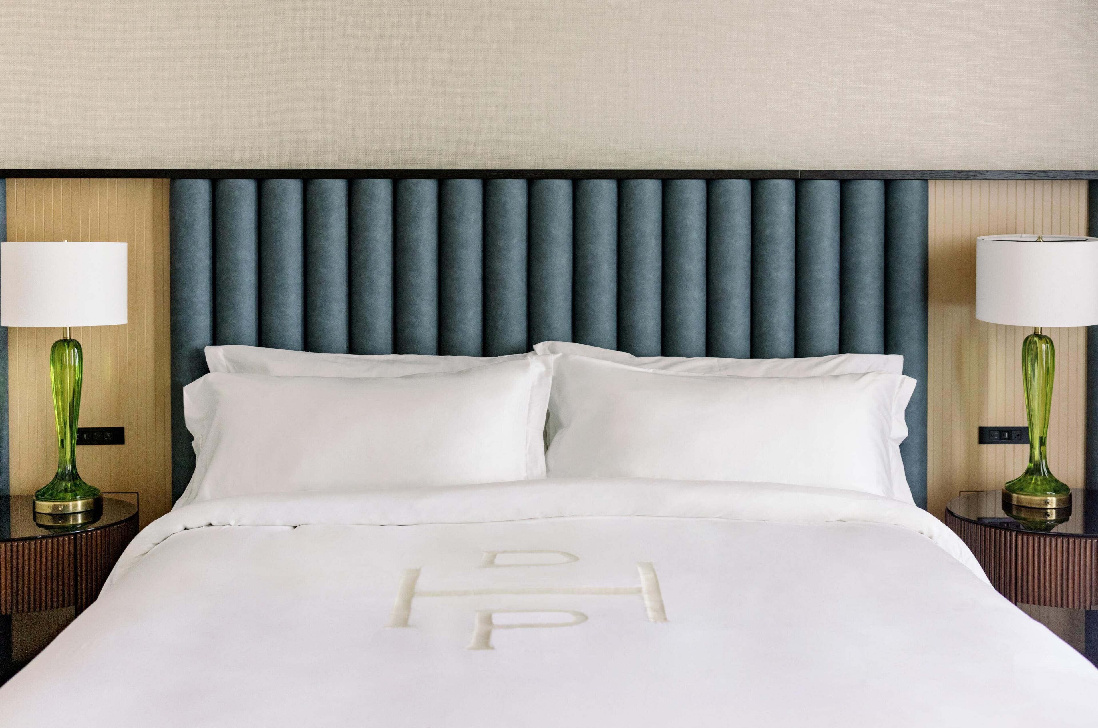 A hotel room with a bed, two bedside tables with lamps, and a headboard.