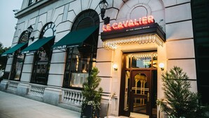 Exterior de Le Cavalier at the Green Room, mostrando una fachada clásica con ventanas arqueadas y un llamativo letrero de neón.