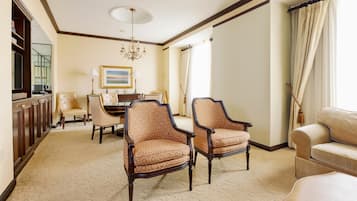 A spacious room with a large window, a chandelier, and a dining area with a table and chairs.