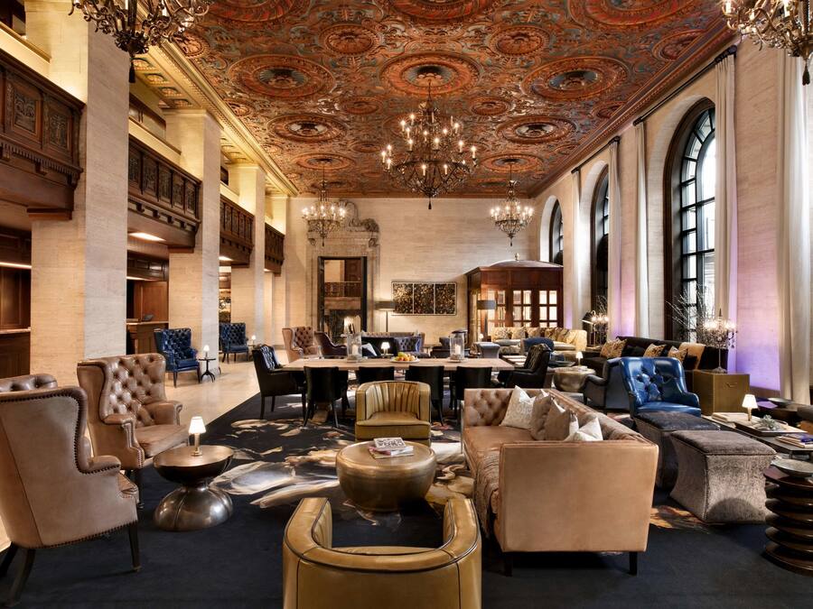 A spacious lobby with a high ceiling, ornate ceiling design, and a central seating area with multiple sofas and chairs.