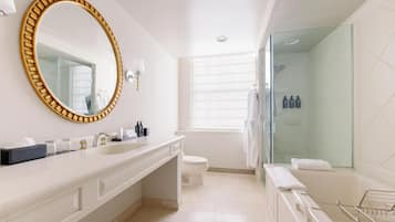 Une salle de bain moderne avec un grand miroir ovale, un lavabo blanc, des toilettes et une douche séparée par une paroi de verre.