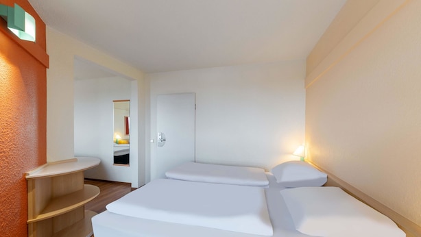 Ein Hotelzimmer mit Bett, Nachttisch, Spiegel und Tür.