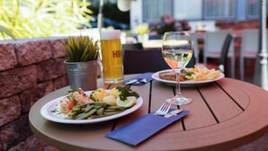 A dining table with plates of food, a glass of white wine, and a beer mug. - Best Western Hotel Ambassador (Baunatal)