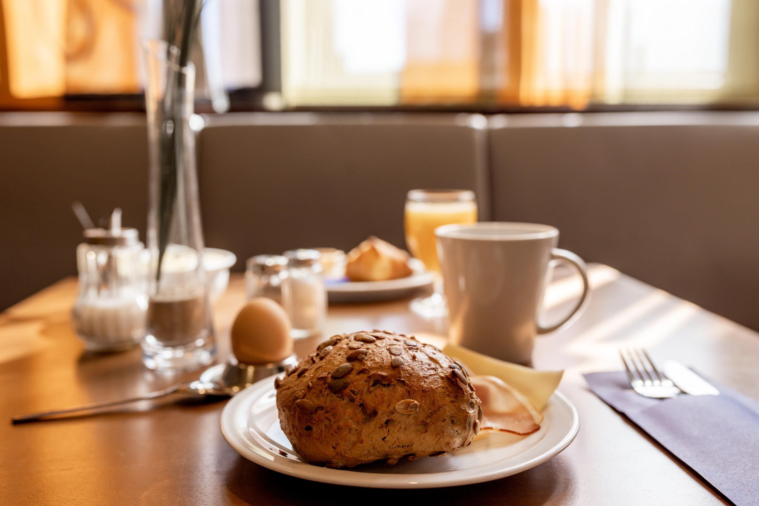 A breakfast setting with a plate of food, a cup, and a glass of juice on a table.