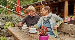Two people sitting at a wooden table outdoors with a potted plant on the table. - Best Western Hotel Ambassador (Baunatal)