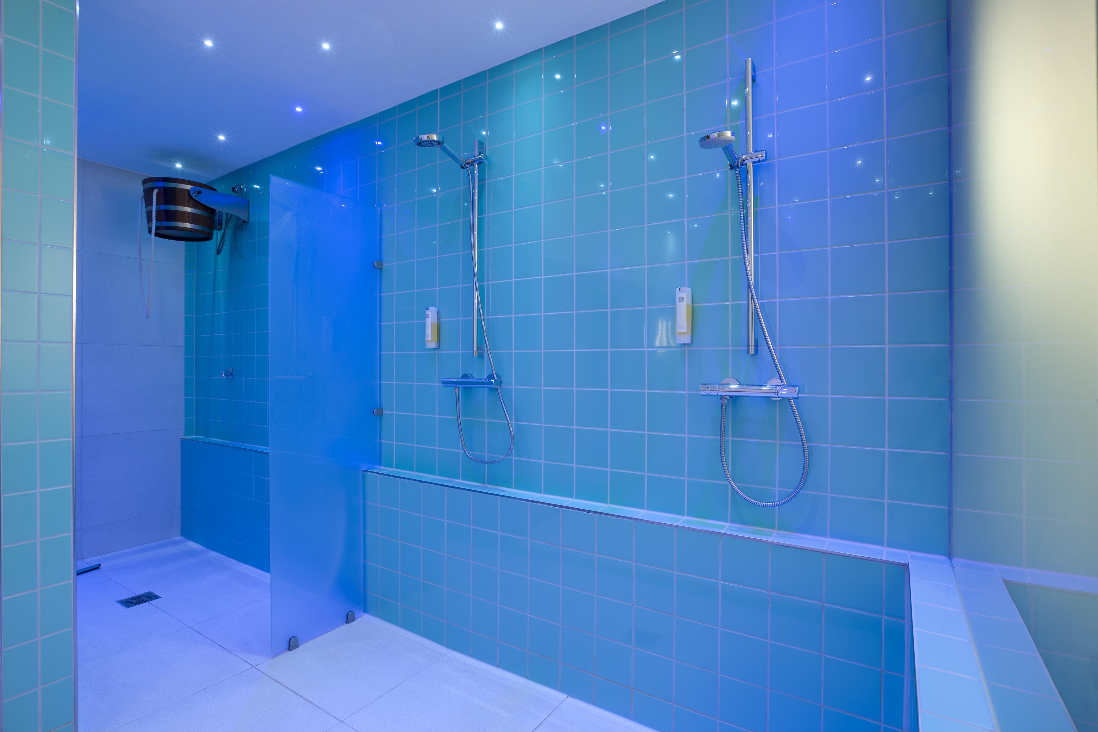 Ein modernes Badezimmer mit blauen Fliesen, einer Glasdusche und einer weißen Badewanne.