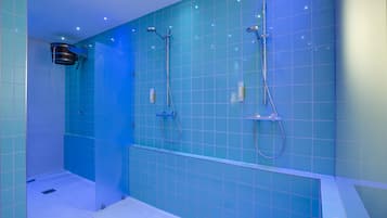 Ein modernes Badezimmer mit blauen Fliesen, einer Glasdusche und einer weißen Badewanne.