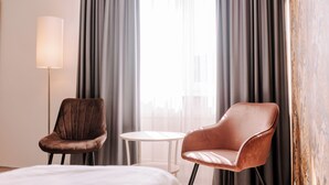 A hotel room with two leather chairs, a small round table, and a bedside lamp. - Best Western Hotel Ambassador (Baunatal)