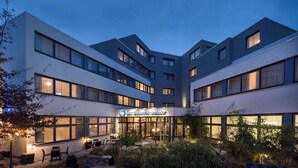 A modern hotel with a courtyard, multiple floors, and a sign reading "Best Western Ambassador". - Best Western Hotel Ambassador (Baunatal)
