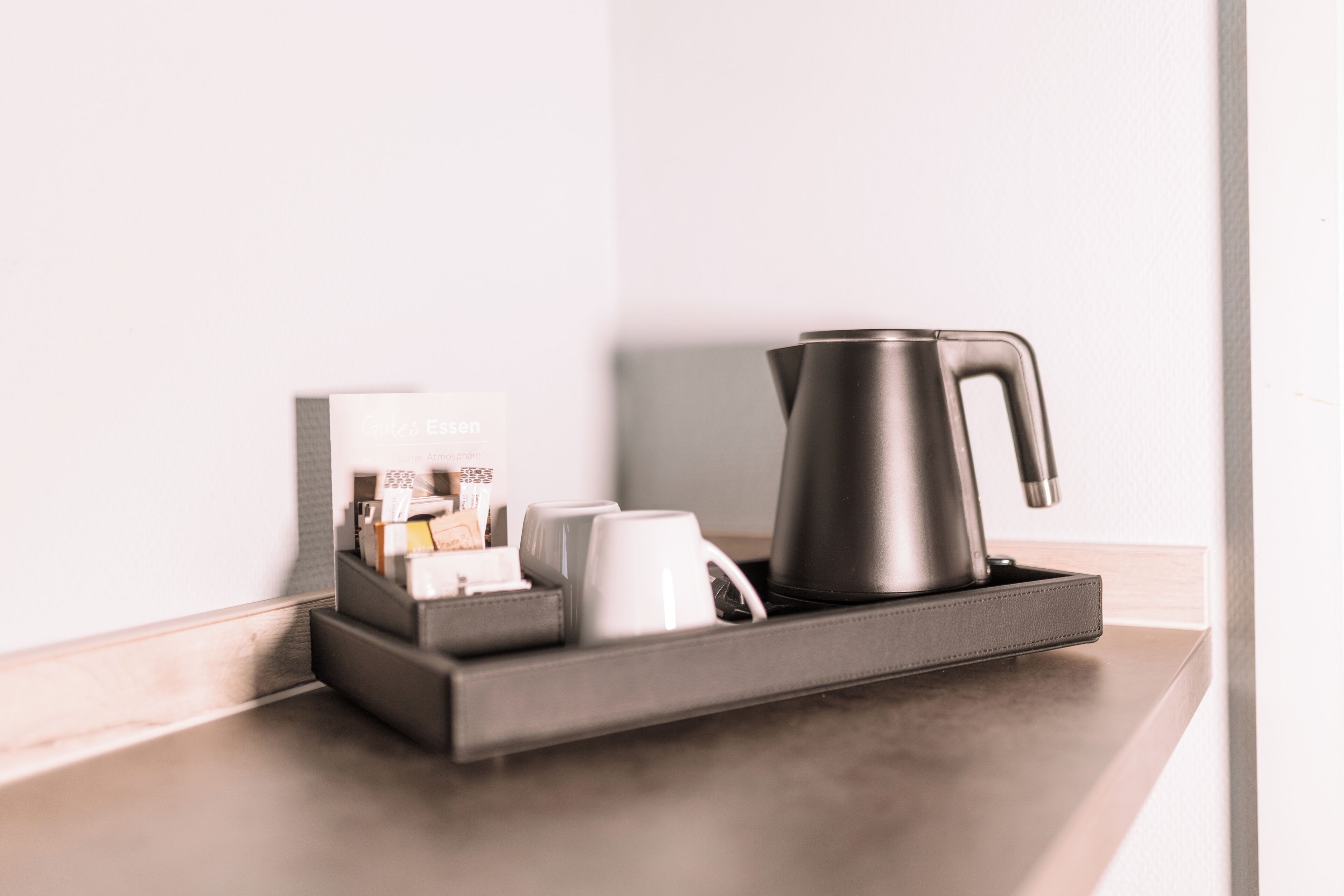 A modern coffee station with a sleek coffee maker, a tray, and a box of coffee pods.