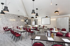 A conference room with multiple tables, red chairs, black pendant lights, a whiteboard, and a projector screen. - Best Western Hotel Ambassador (Baunatal)