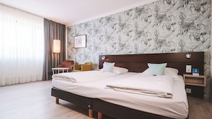 A hotel room with a large bed, a nightstand, a lamp, and a chair. - Best Western Hotel Ambassador (Baunatal)