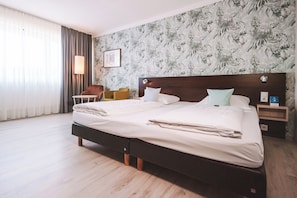 Une chambre d’hôtel avec un grand lit, une table de chevet, une lampe et une chaise.