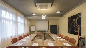A conference room with a long table, red chairs, a projector screen, and a large abstract painting on the wall. - Best Western Hotel Ambassador (Baunatal)