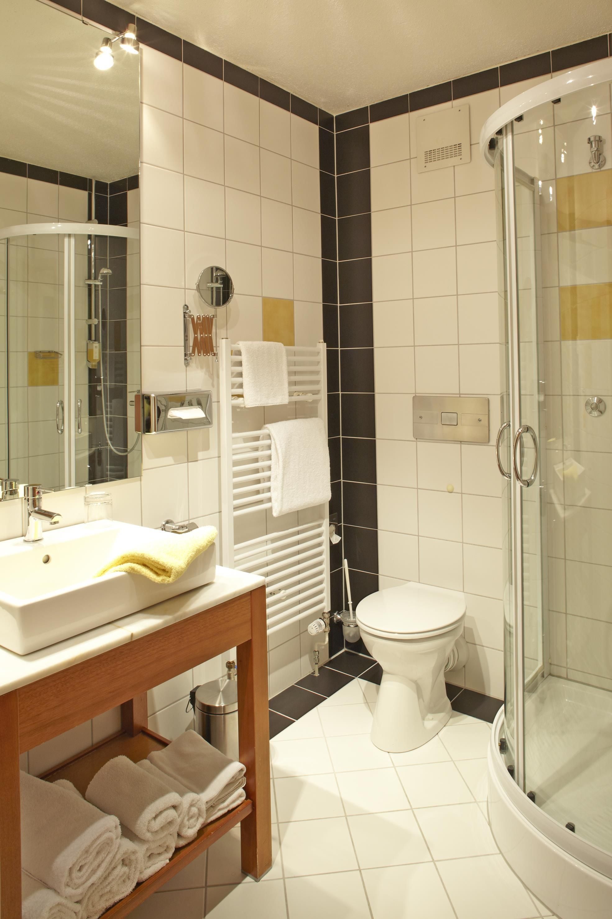 Et stilfuldt badeværelse med brusekabine i glas, et hvidt håndvaskarrangement og et toilet.