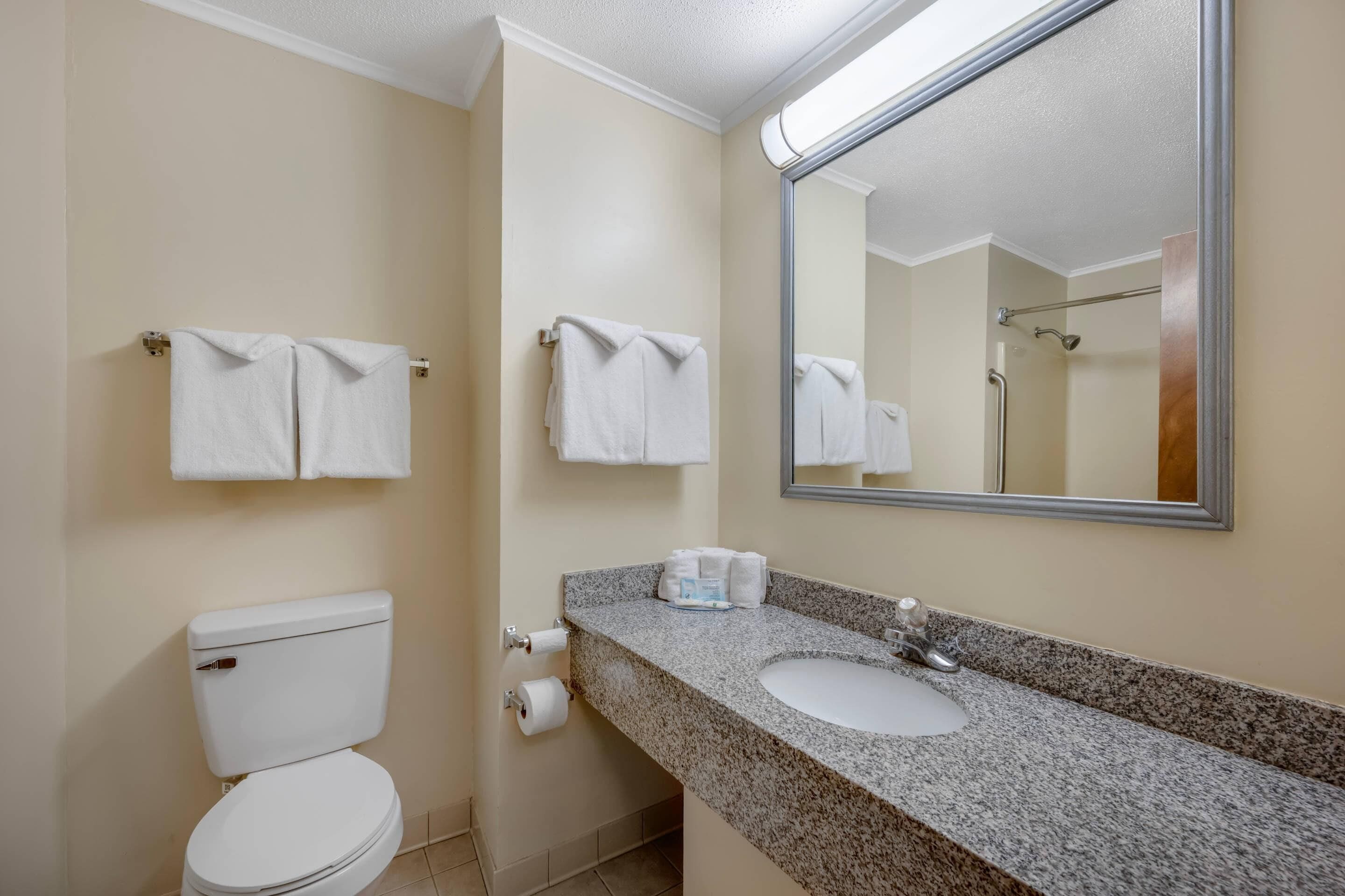 A bathroom with a toilet, sink, and two towel racks with towels.