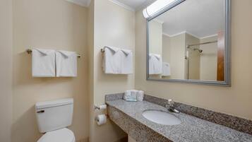 A bathroom with a toilet, sink, and two towel racks with towels.