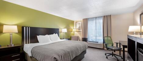 Ein Hotelzimmer mit Bett, Schreibtisch, Stuhl und einem großen Fenster.