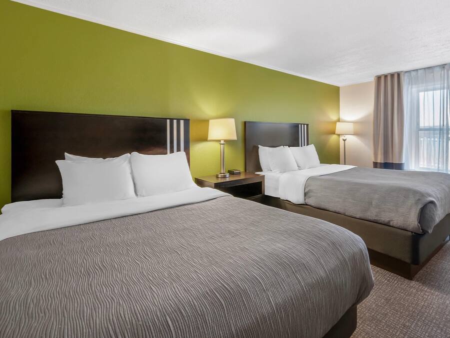 A hotel room with two beds, green walls, and a window with curtains.