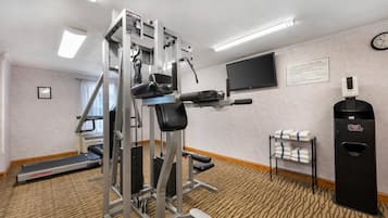 Een fitnessruimte met cardioapparatuur, een televisie en een handdoekhouder.