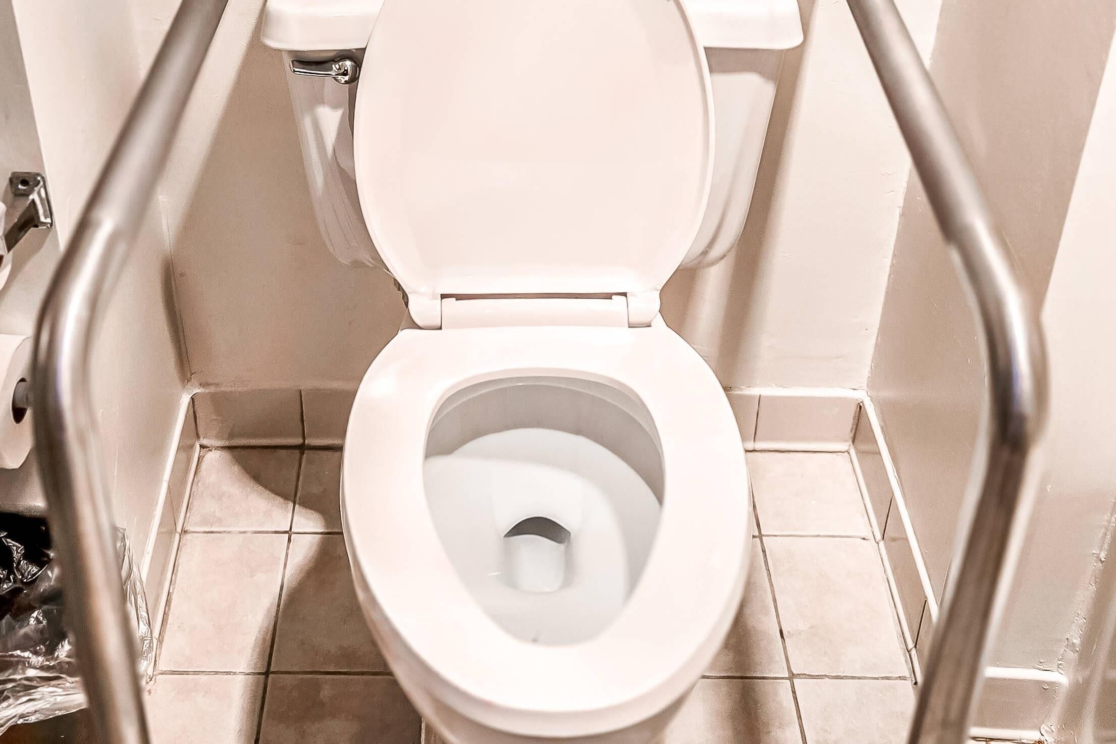 A toilet with a raised seat and grab bars, indicating accessibility features.