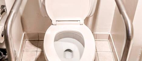 A toilet with a raised seat and grab bars, indicating accessibility features.