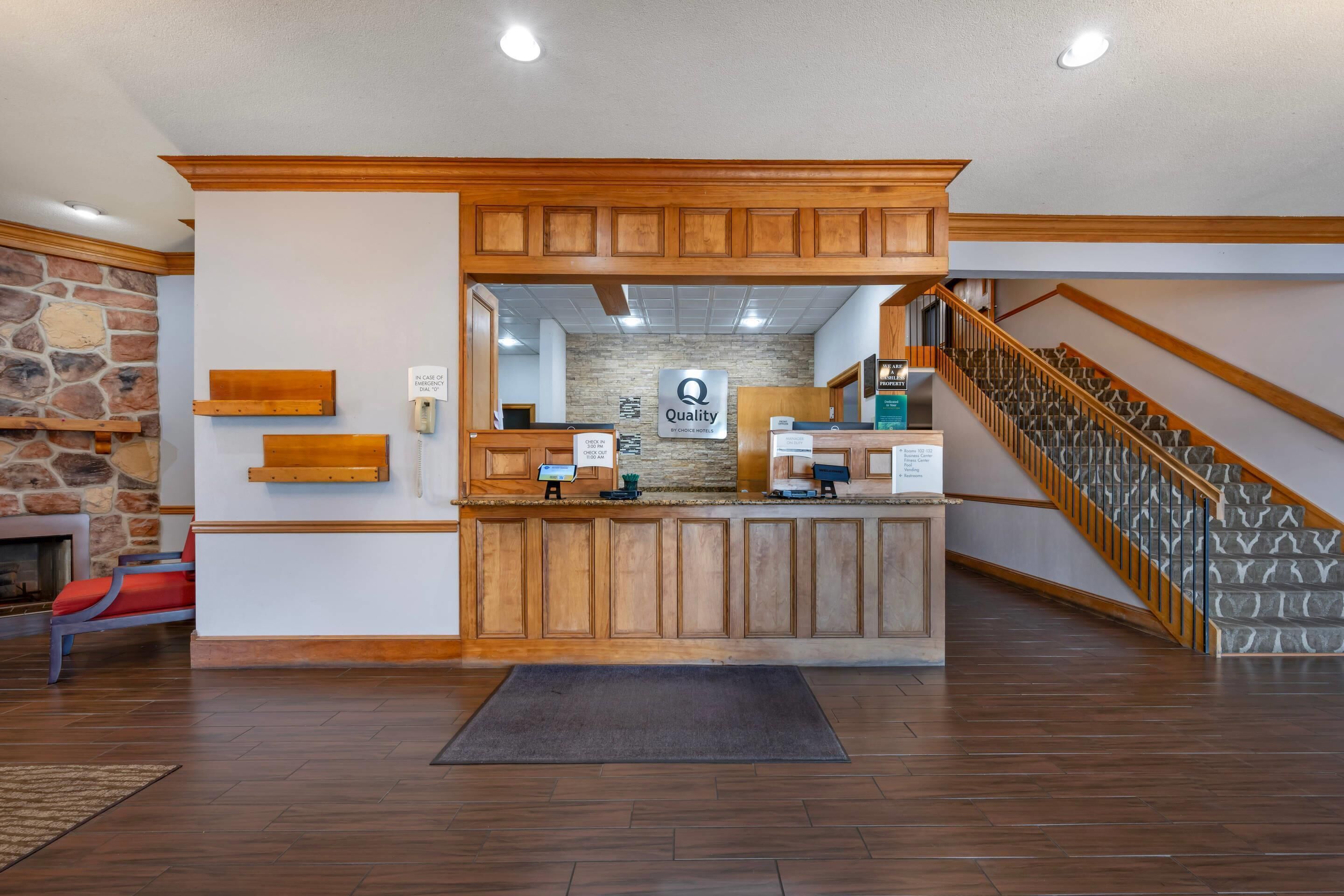A reception area with a stone wall, wooden reception desk, and a staircase.