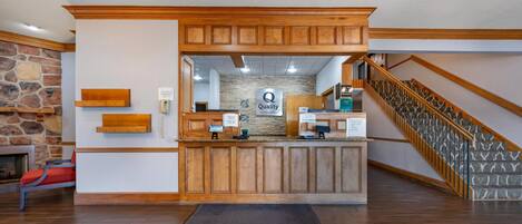 A reception area with a stone wall, wooden reception desk, and a staircase.