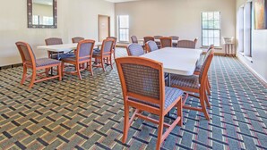 Une salle de conférence dotée d’une grande table et de chaises, d’un tapis à motifs et de grandes fenêtres.
