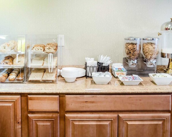 A breakfast buffet setup with various food items and serving utensils.