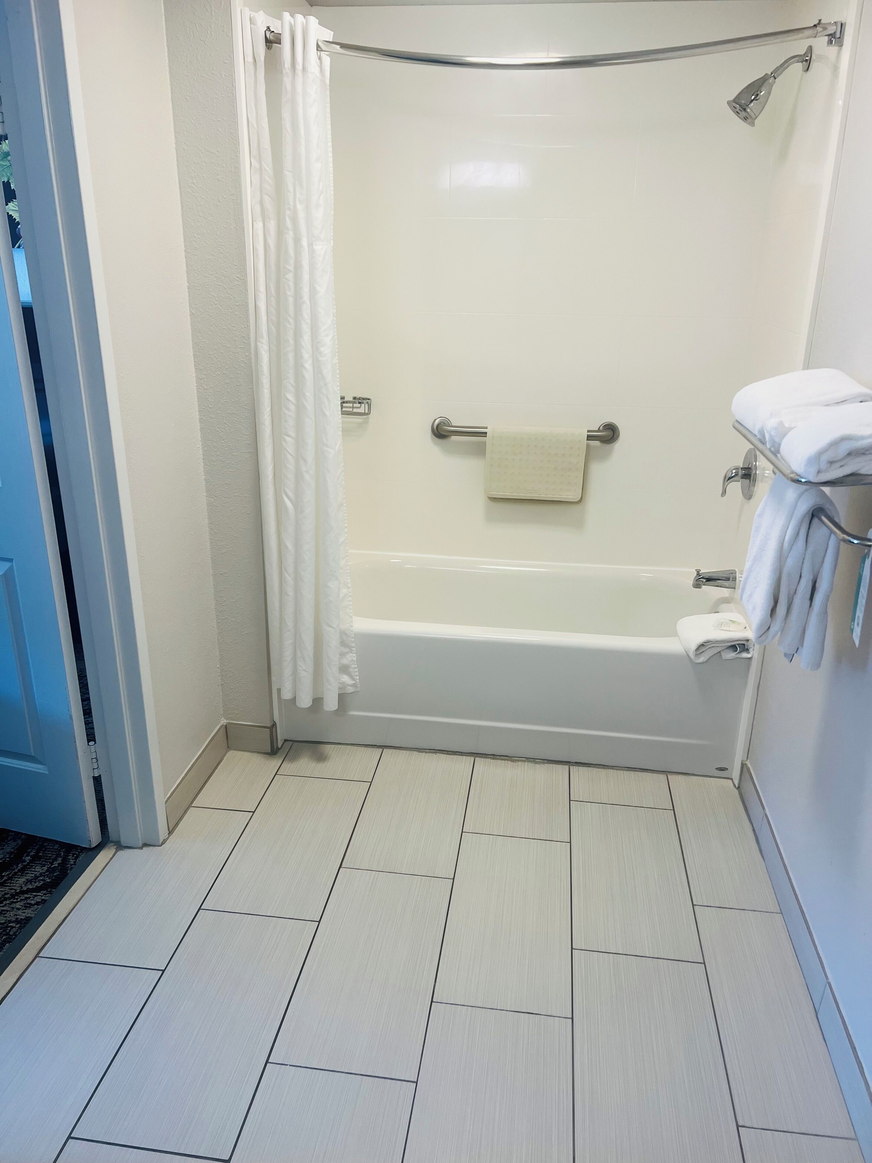 A bathroom with a bathtub, a shower, and a towel rack.