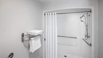 A modern bathroom with a walk-in shower, a towel rack with folded towels, and a grab bar for safety.