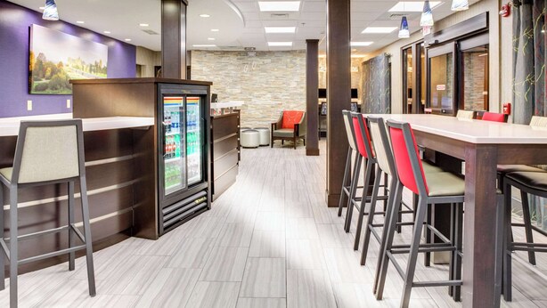 A modern hotel lobby with a reception desk, bar area, and seating. - Clarion Pointe Biltmore Village (Asheville)