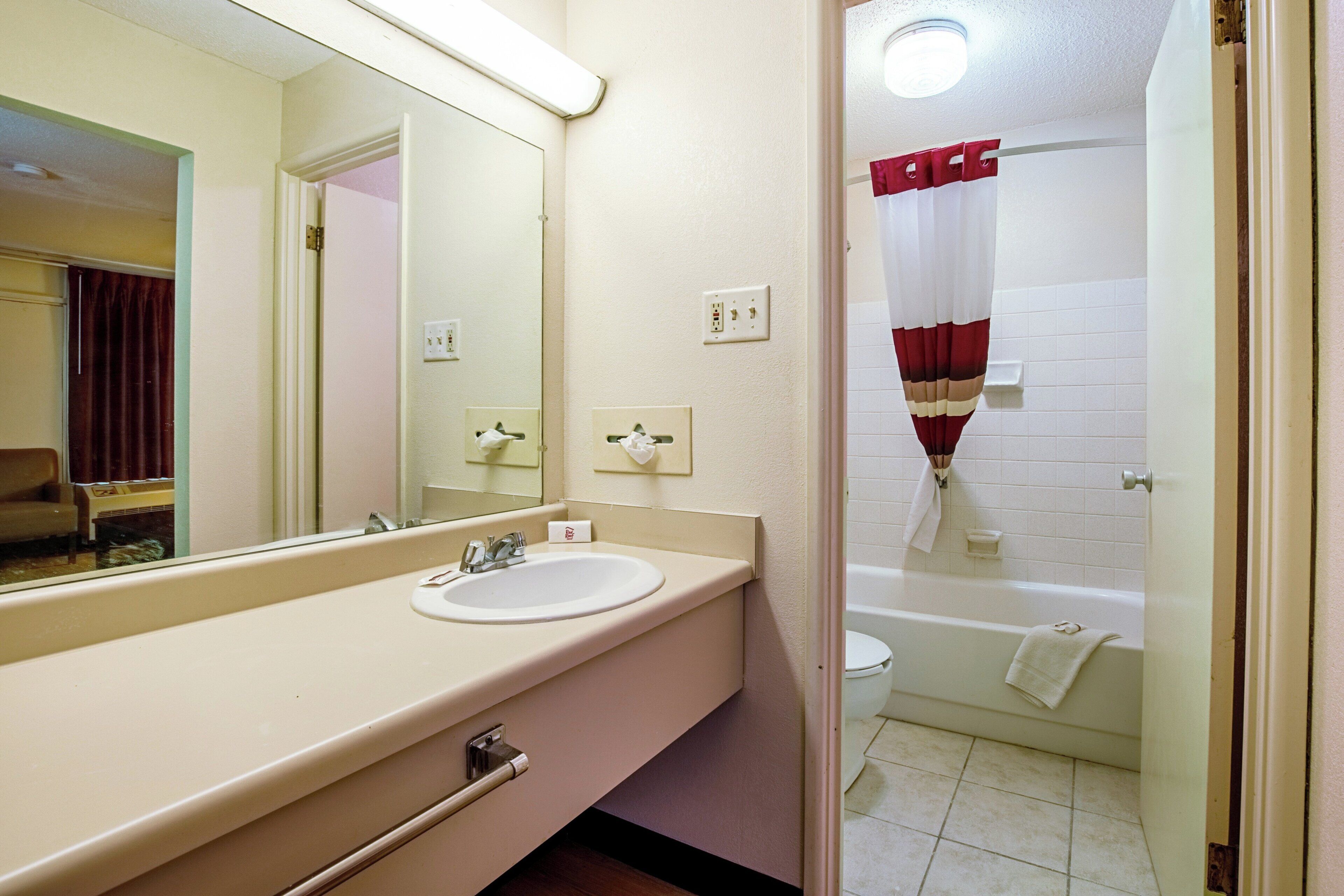 A bathroom with a sink, mirror, and a shower area.