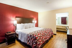 Habitación de hotel con cama, lámparas de noche, mesita de noche, espejo y ventana.
