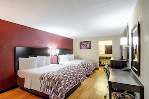Una habitación de hotel con una cama grande, un escritorio y un espejo.