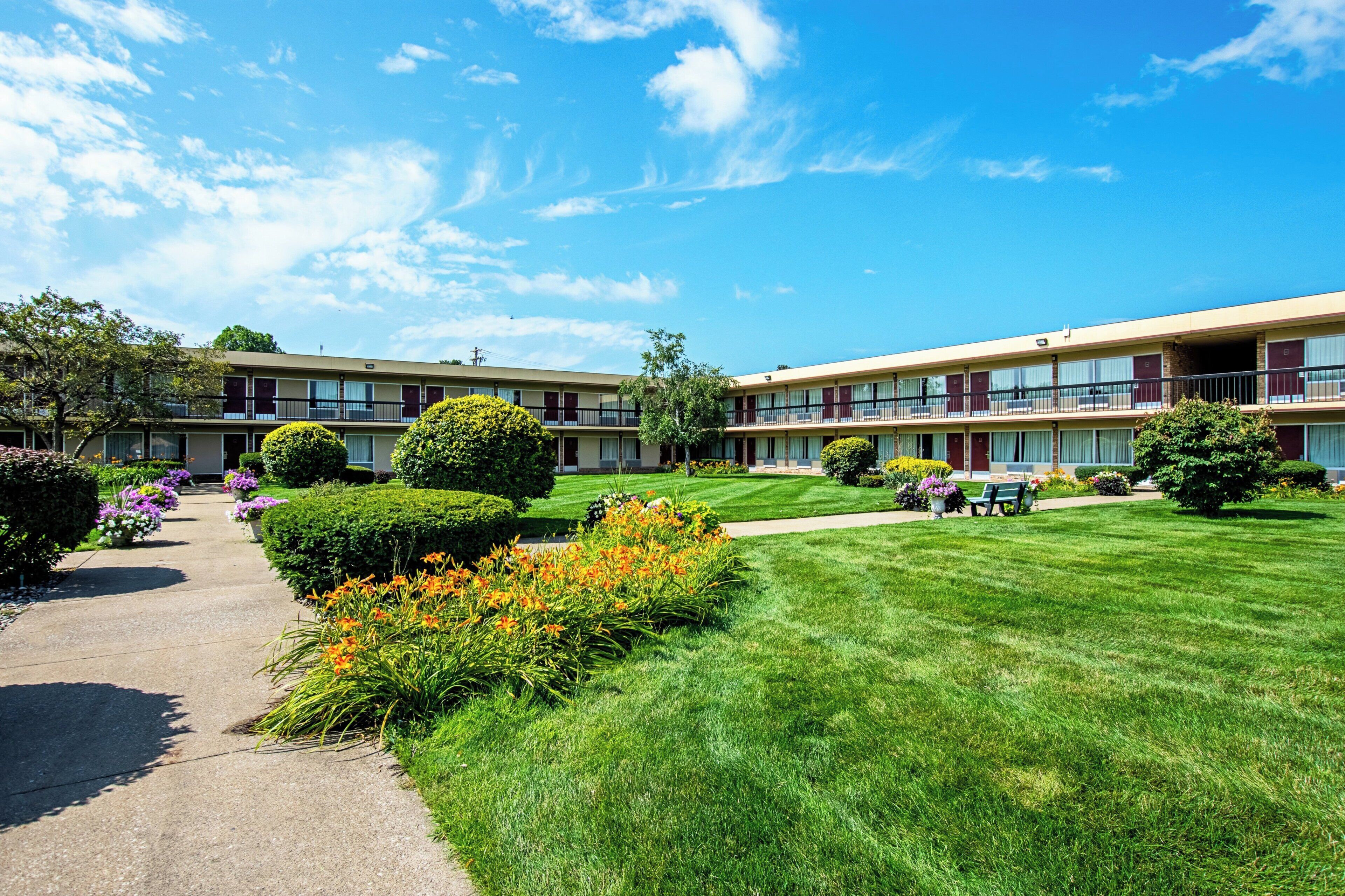 A two-story motel with a well-maintained lawn and flower beds.