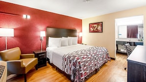A hotel room with a large bed, a desk, a chair, and a window. - Red Roof Inn Battle Creek (Battle Creek)
