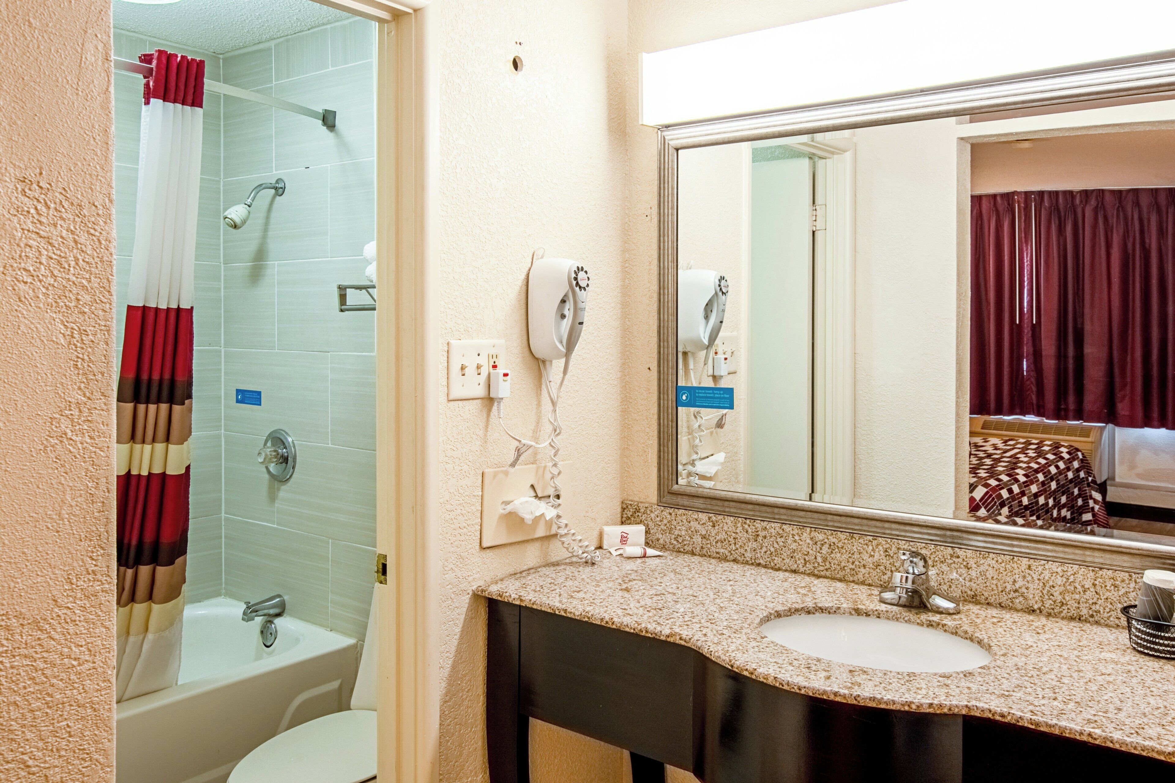 A bathroom with a bathtub, a shower, a sink, and a mirror.