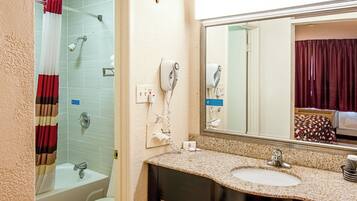 A bathroom with a bathtub, a shower, a sink, and a mirror.