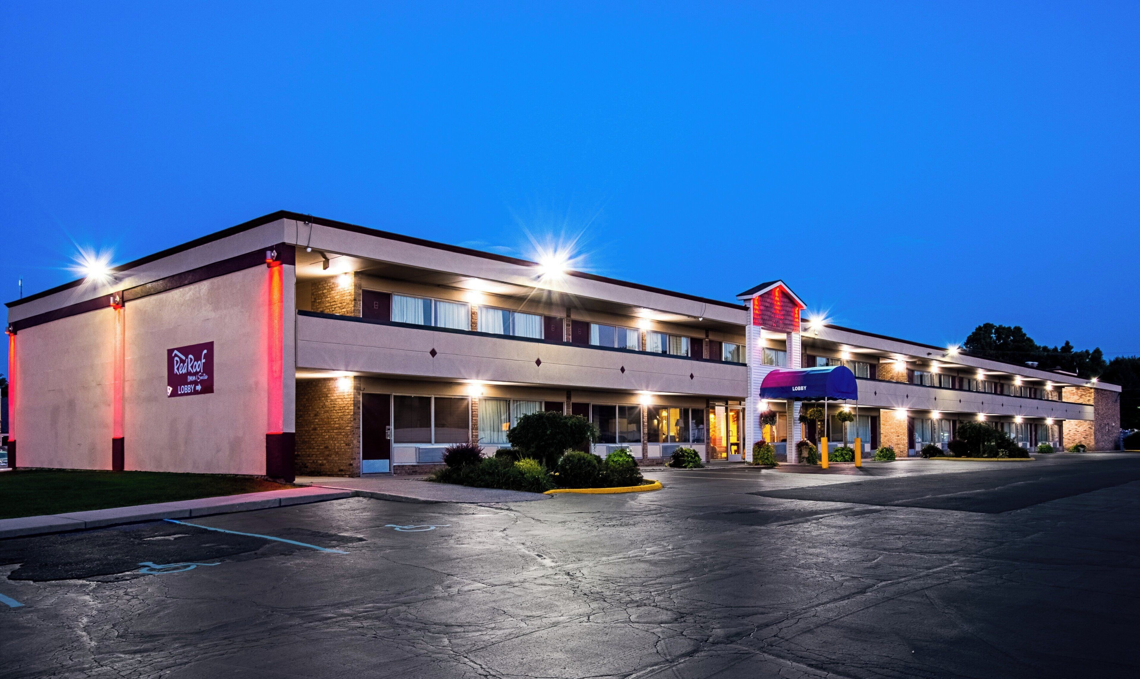 Un motel avec un bâtiment à deux étages, un hall d’accueil bien visible et un parking.