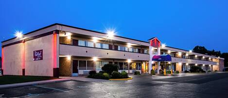 Un motel avec un bâtiment à deux étages, un hall d’accueil bien visible et un parking.