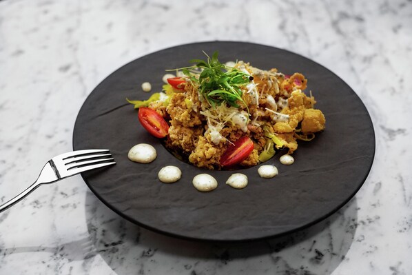 A black plate with food on a marble surface.