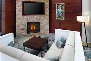 Una sala de estar moderna con chimenea, un televisor de pantalla plana, un sofá, una mesa de centro y una lámpara de pie.