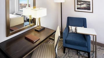 Une chambre d’hôtel équipée d’un bureau, d’une chaise, d’une lampe et d’un tableau encadré au mur.