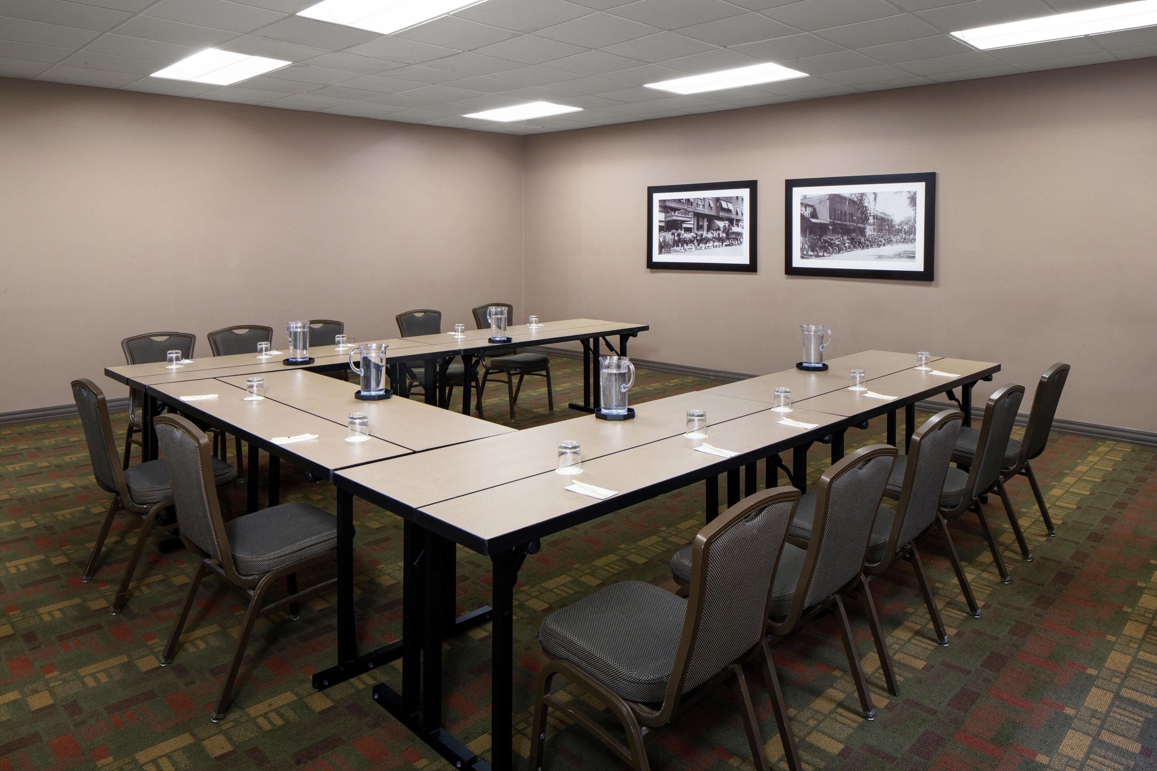 A conference room with a long table, chairs, and two framed pictures on the wall.